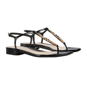 Black sandals with gold chain detail on a light gray background