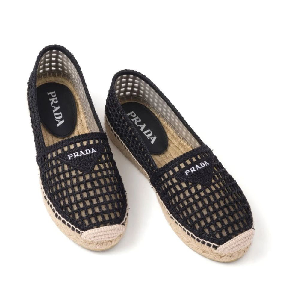 Black espadrille shoes with Prada logo on a white background