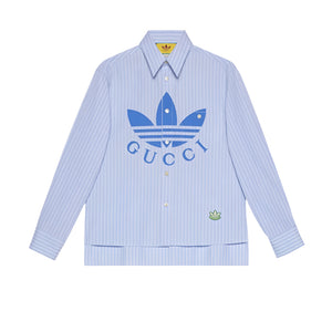 Light blue striped shirt with Gucci and Adidas logos on a light gray background