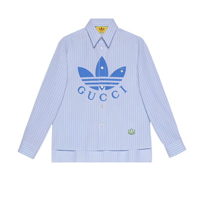 Light blue striped shirt with Gucci and Adidas logos on a light gray background