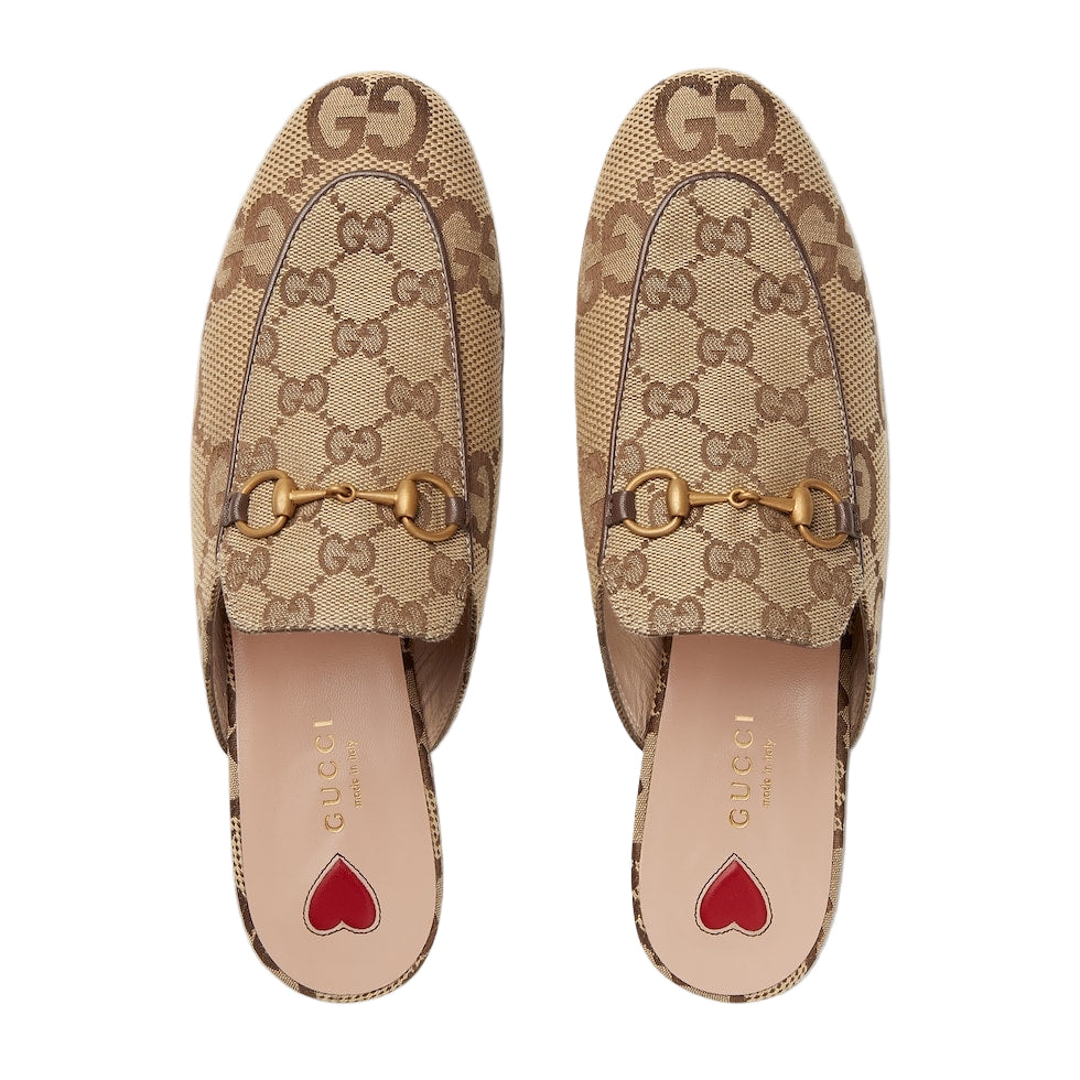 Pair of Gucci loafers with monogram pattern and gold hardware on a light gray background