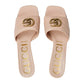 Pair of Gucci slides with gold logo and text on a light gray background