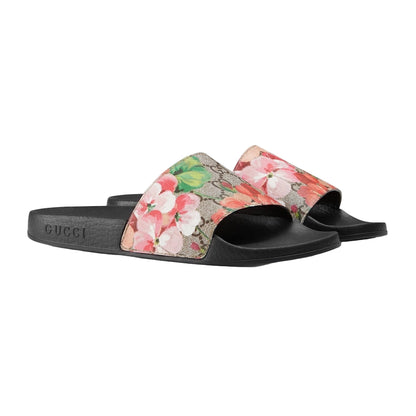 Floral slide sandals with Gucci logo on a light gray background