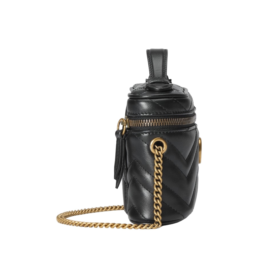 Black quilted handbag with gold chain strap on a light gray background