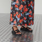 Person wearing black sandals and floral pants on a textured floor.