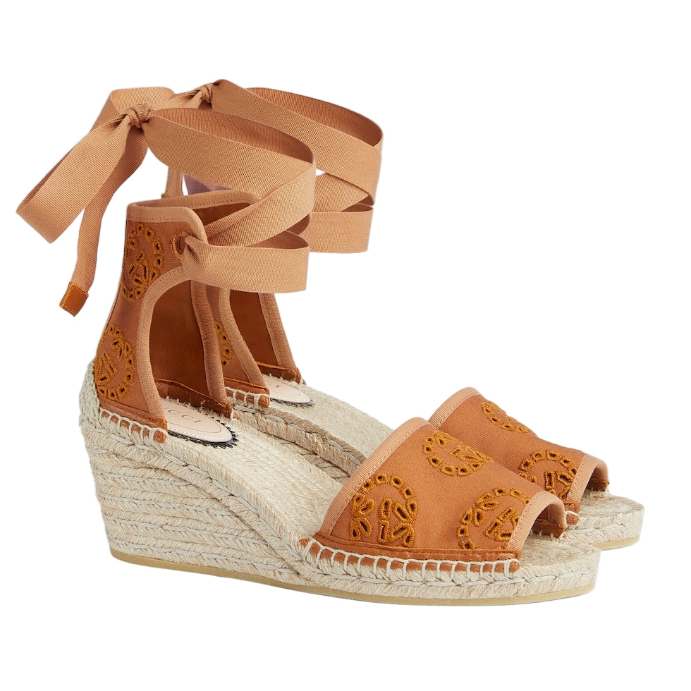 Tan wedge sandals with espadrille sole on a light gray background