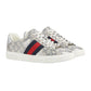 Pair of Gucci sneakers with a patterned design and red and blue stripe on a light gray background