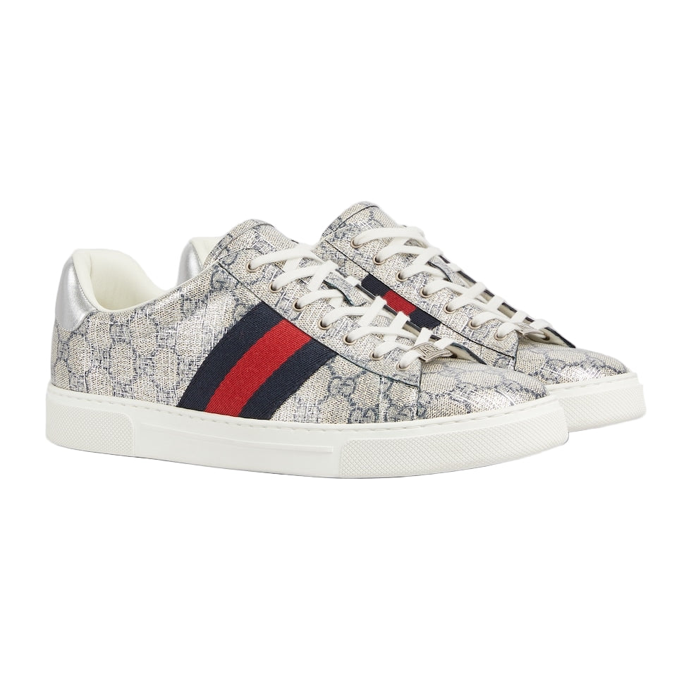 Pair of Gucci sneakers with a patterned design and red and blue stripe on a light gray background