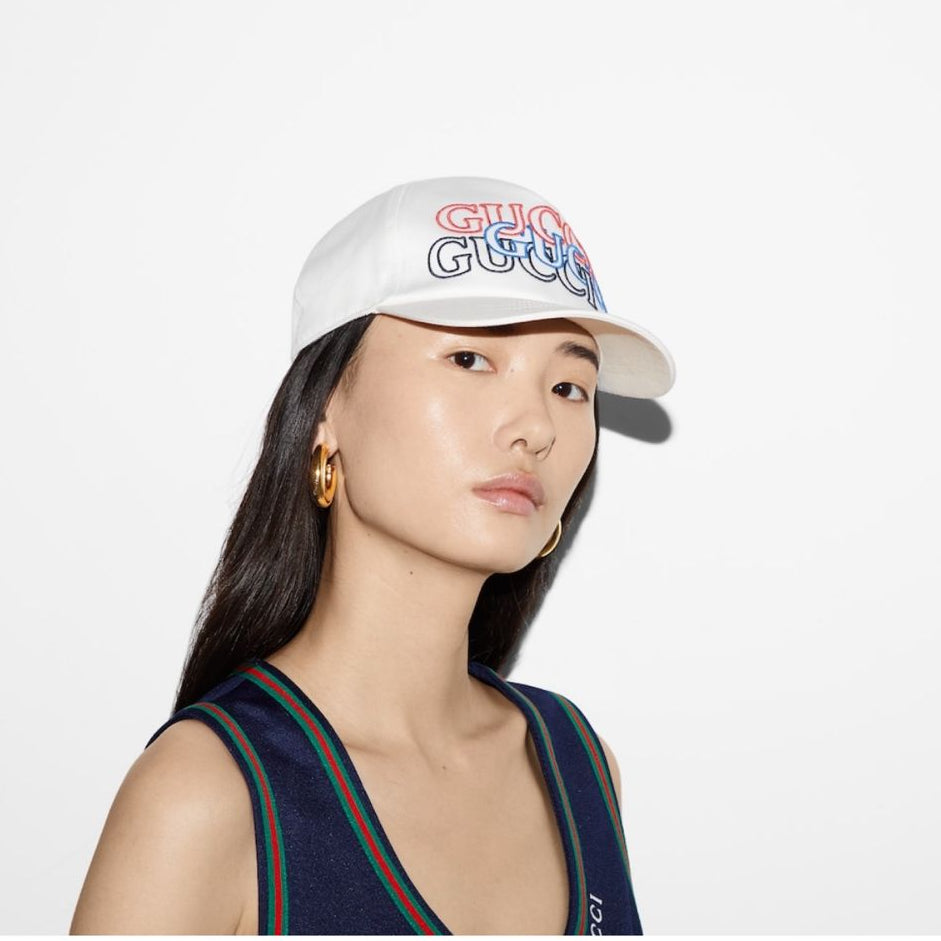 Woman wearing a white cap with colorful text on a plain background