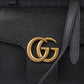 Black leather handbag with gold Gucci logo on a black background