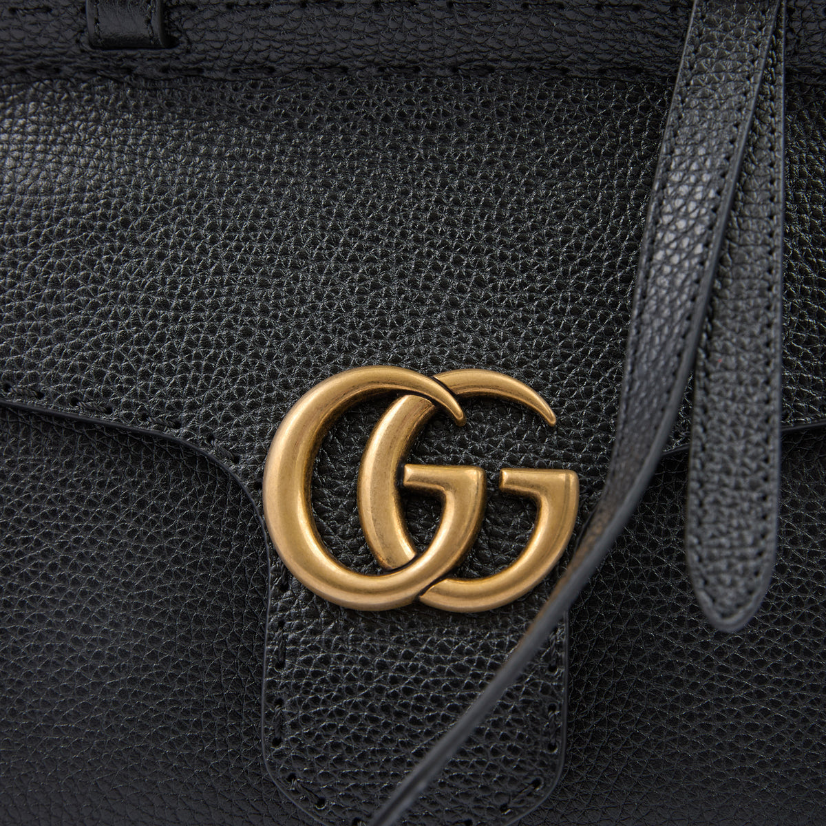 Black leather handbag with gold Gucci logo on a black background