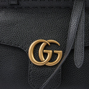 Black leather handbag with gold Gucci logo on a black background