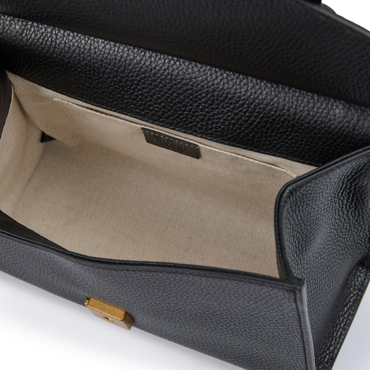 Black leather handbag with gold hardware on a white background