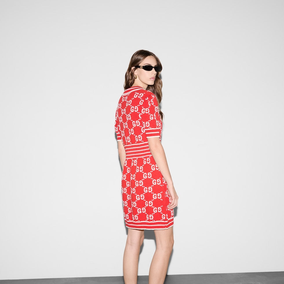 Woman wearing a Gucci red dress with a pattern, standing against a plain background