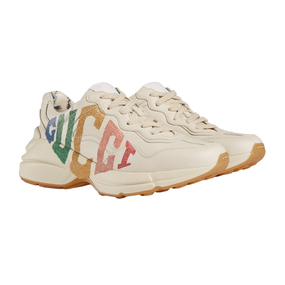Beige sneakers with colorful 'Gucci' branding on a light gray background