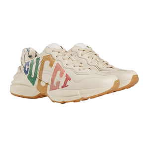Beige sneakers with colorful 'Gucci' branding on a light gray background