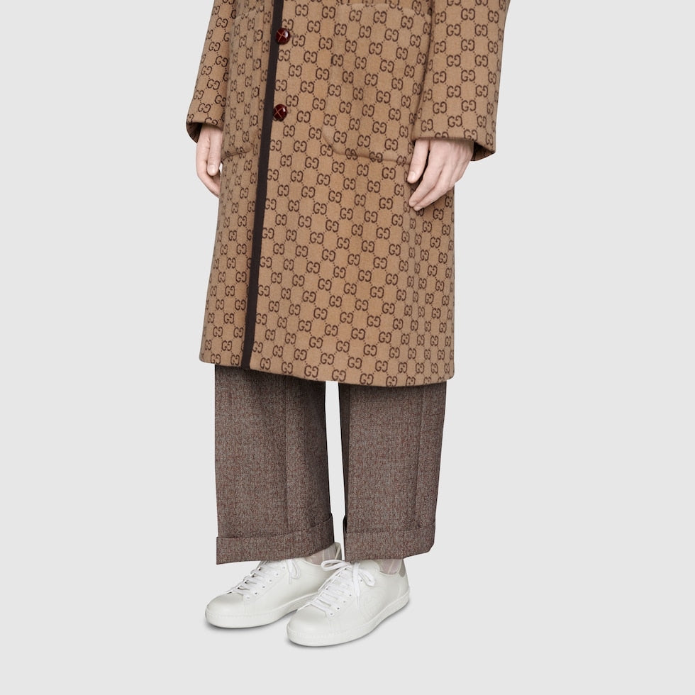 Person wearing a brown patterned coat with matching pants on a white background