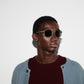 Person wearing sunglasses and a light blue cardigan over a dark sweater on a white background