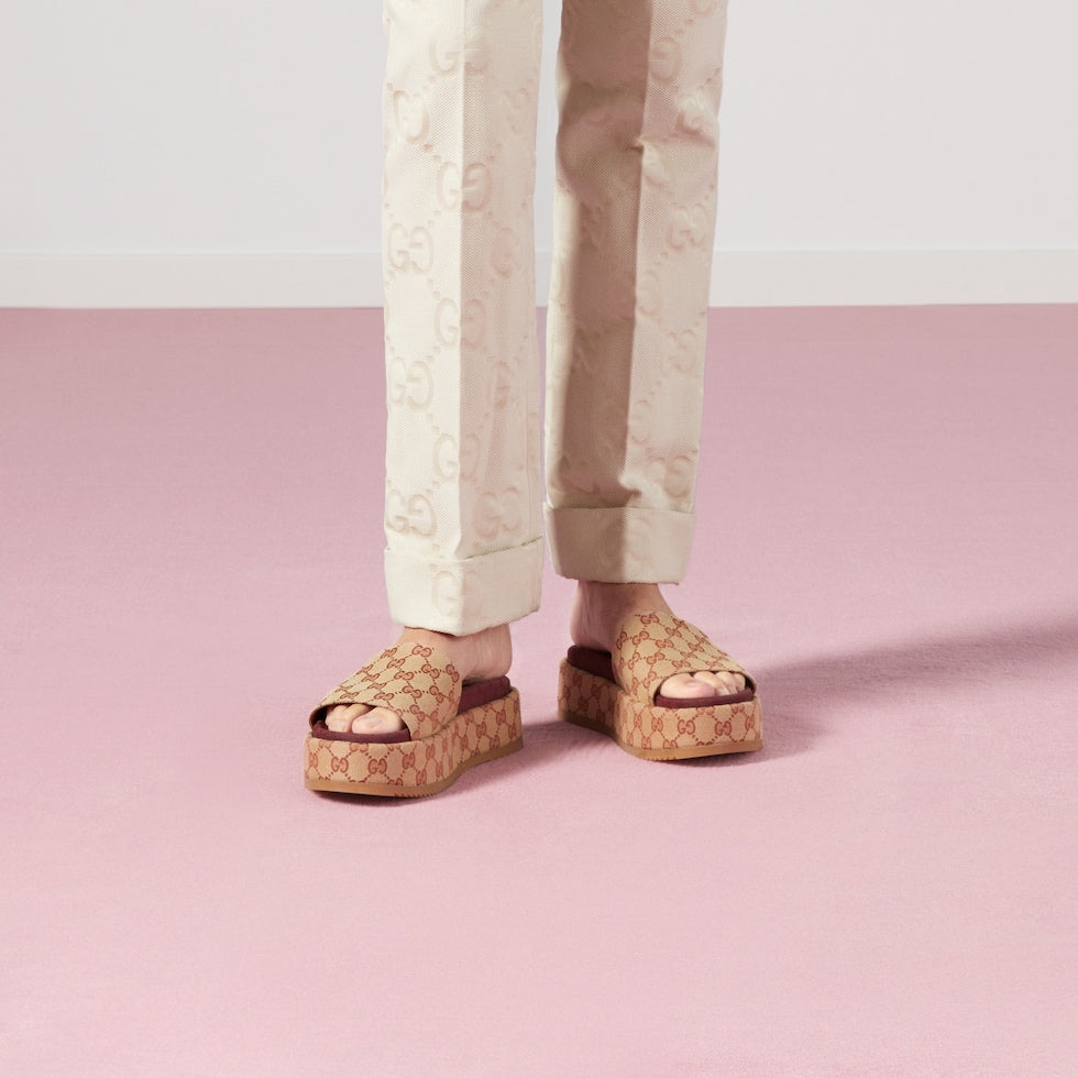 Person wearing patterned sandals on a pink background