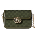 Green handbag with gold chain and logo on a light gray background