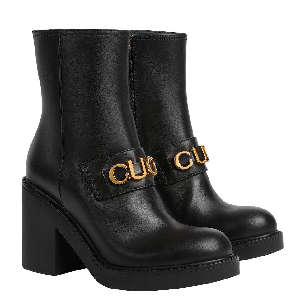 Black ankle boots with gold Gucci logo on a light gray background