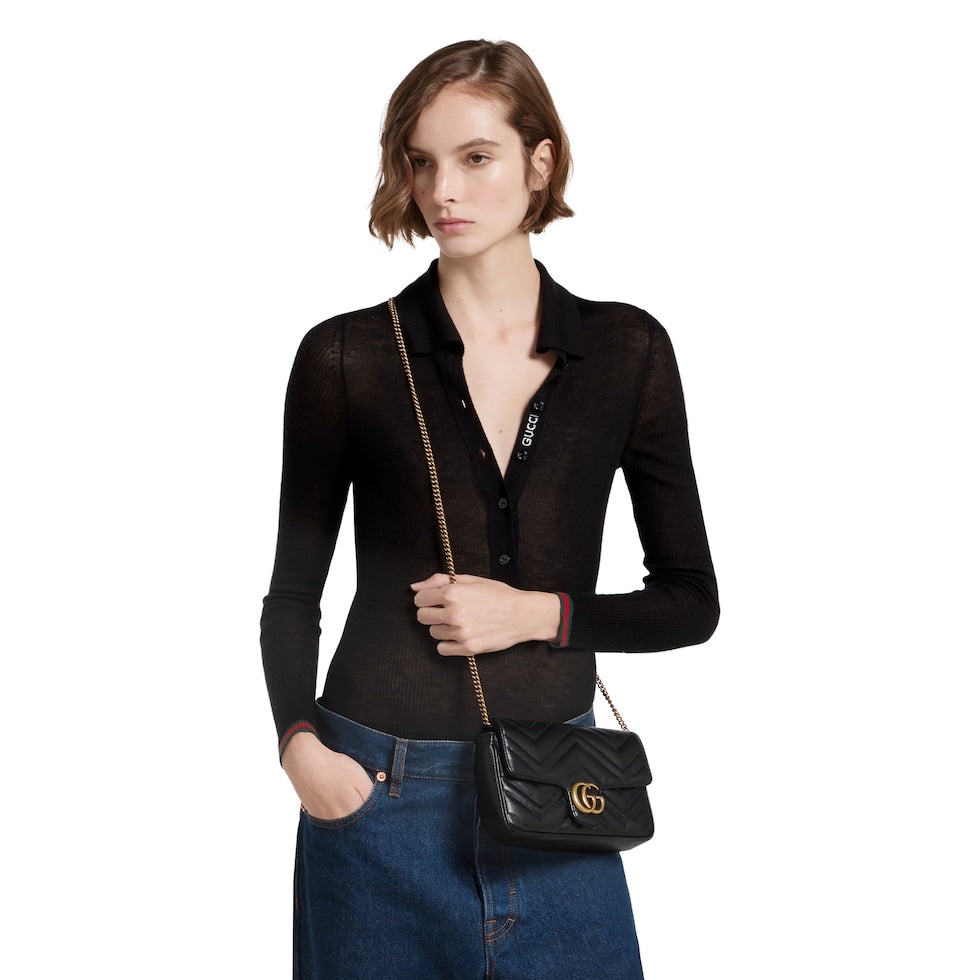 Woman holding a black handbag with a gold chain strap on a white background