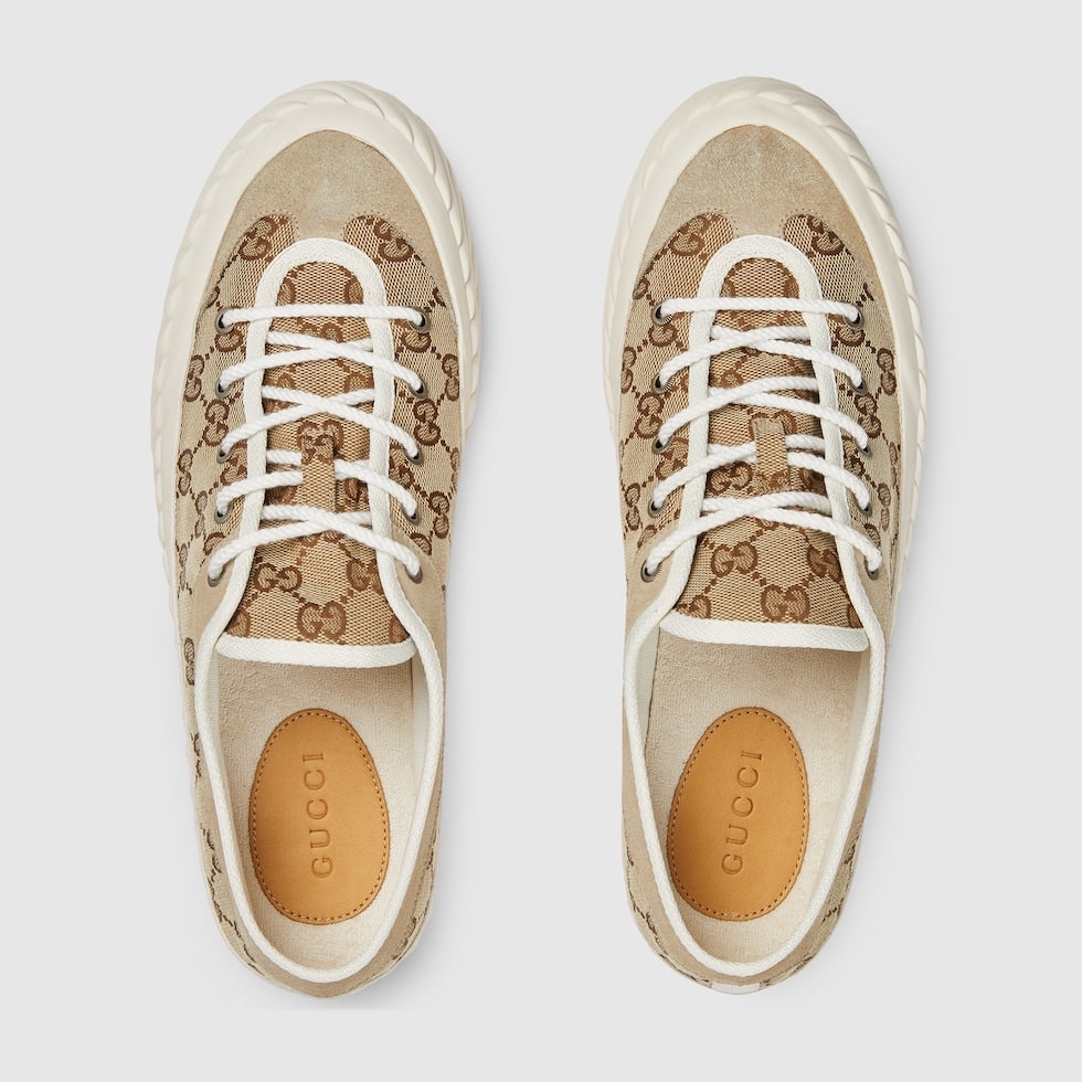 Pair of Gucci sneakers with brown and beige pattern on a light gray background
