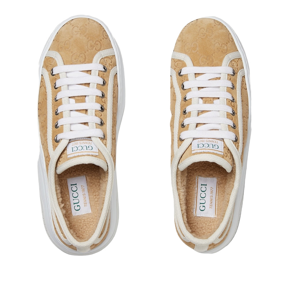 Pair of Gucci sneakers with tan suede upper and white laces on a light gray background
