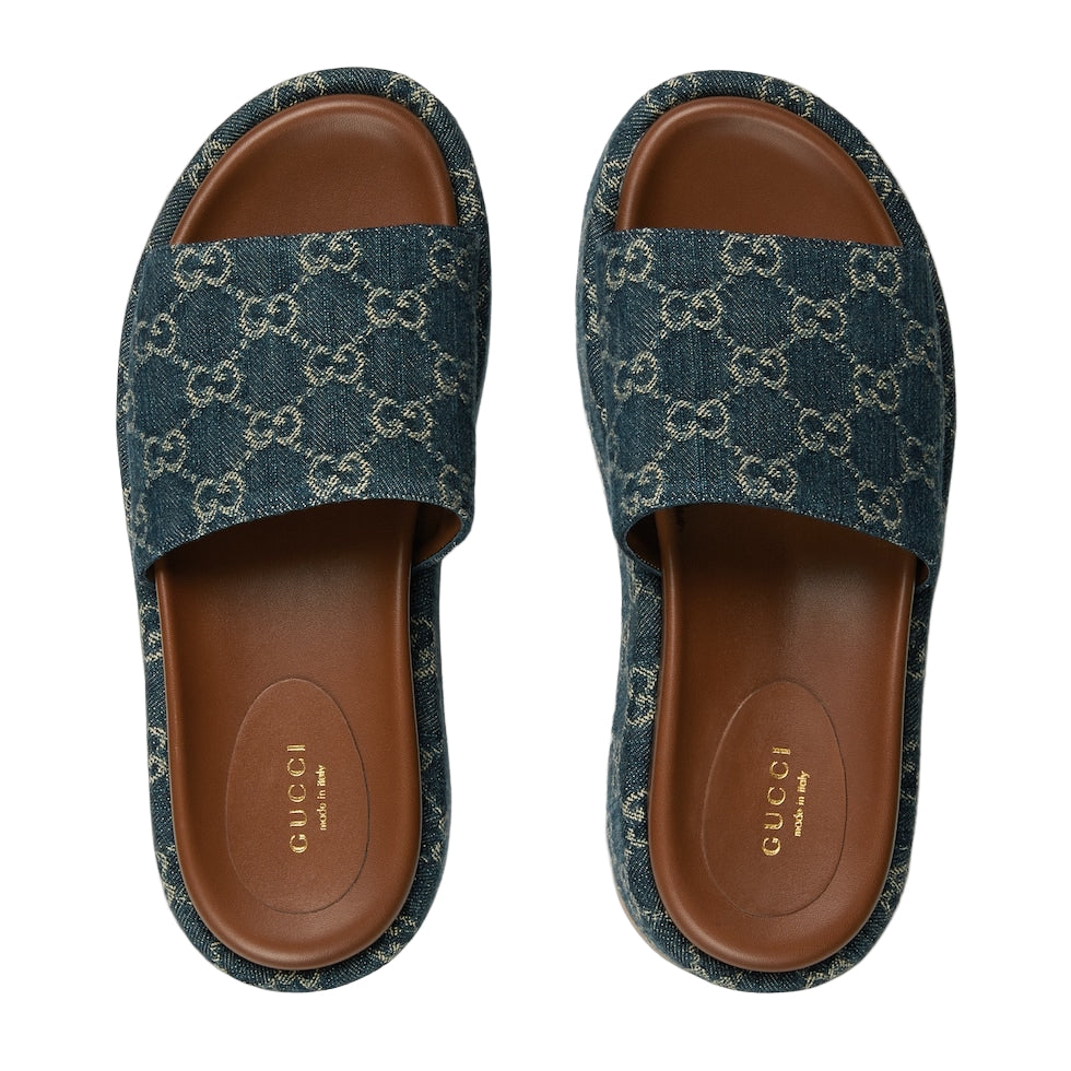 Pair of Gucci slides with blue patterned uppers and brown soles on a white background