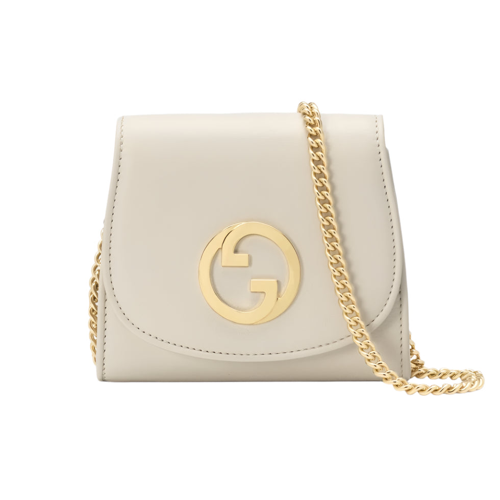 Beige Gucci handbag with gold chain and logo on a light gray background