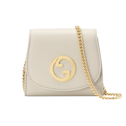 Beige Gucci handbag with gold chain and logo on a light gray background