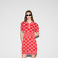 Woman wearing a Gucci red dress with a pattern, standing against a plain background