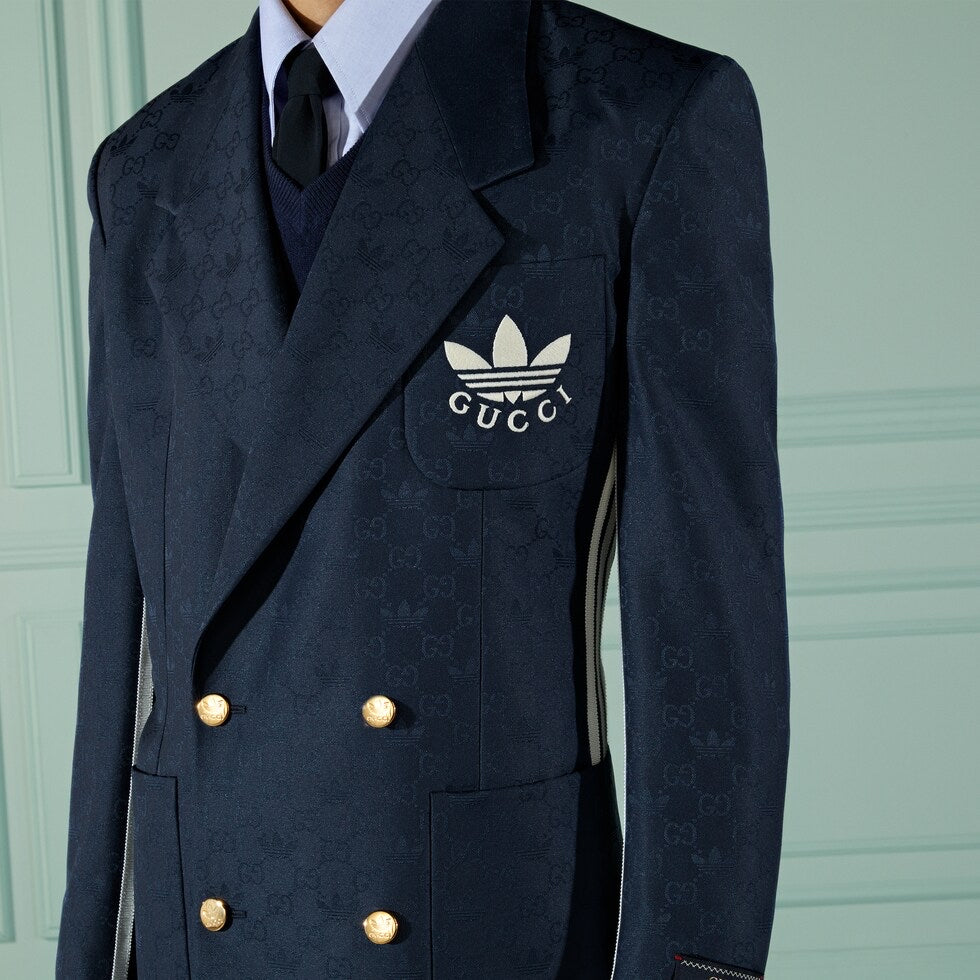Navy blue Gucci jacket with Adidas logo on a light green background