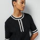 Woman wearing a blackGucci  dress with white trim on a plain background