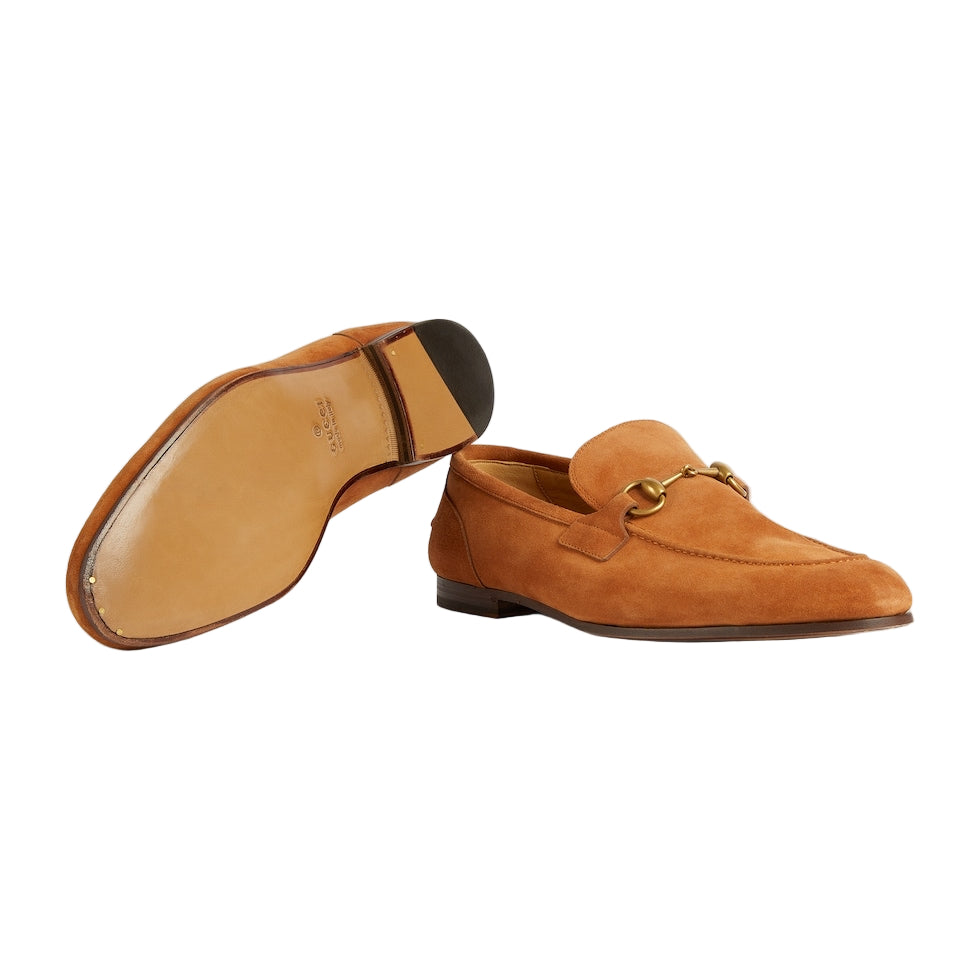 Brown suede loafer shoe with gold buckle on a light gray background