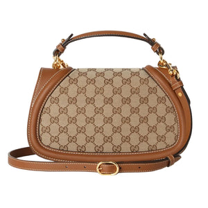 Designer handbag with patterned fabric and brown leather accents on a light gray background