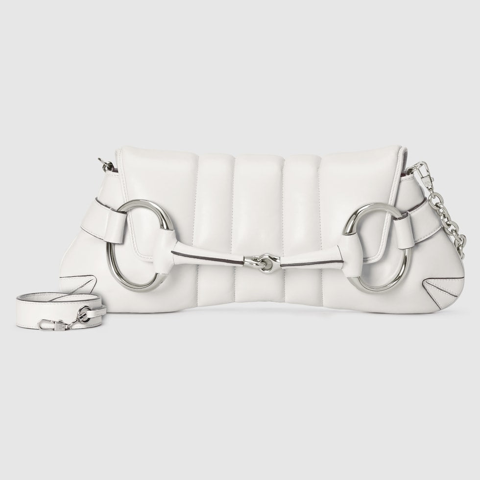 White quilted handbag with silver chain and clasp on a light gray background