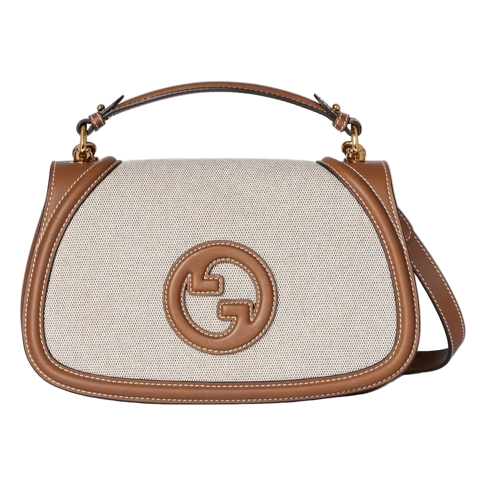Designer handbag with brown leather accents on a light gray background