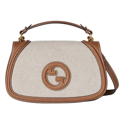 Designer handbag with brown leather accents on a light gray background