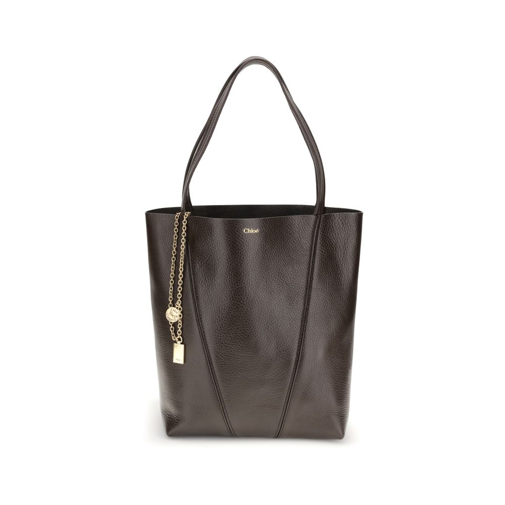 Black leather tote bag with gold chain and tag on a white background