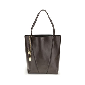 Black leather tote bag with gold chain and tag on a white background