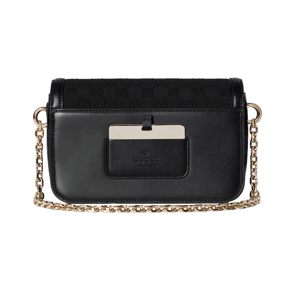 Black handbag with gold chain strap on a light gray background