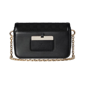 Black handbag with gold chain strap on a light gray background