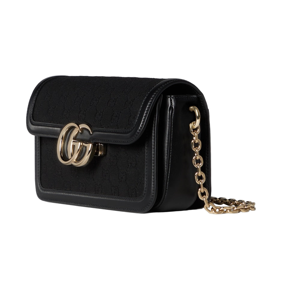 Black handbag with gold chain on a light gray background