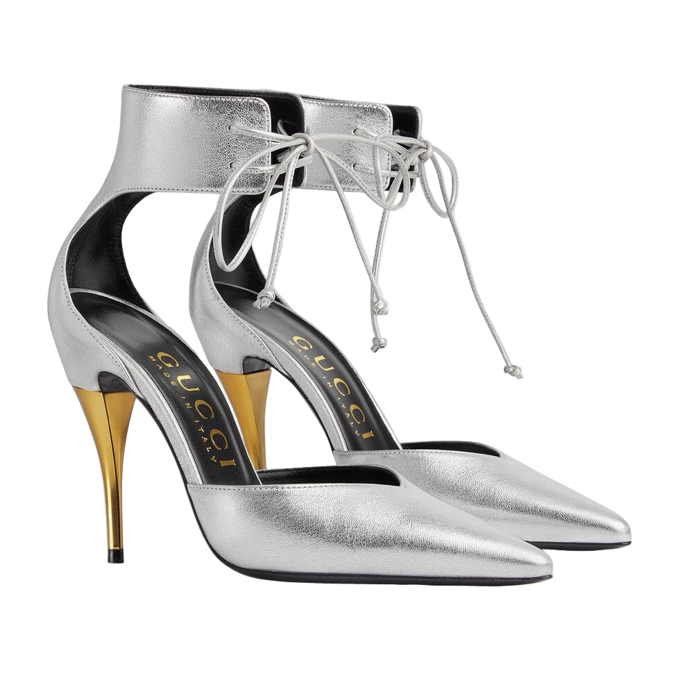 Silver high-heeled shoes with gold accents on a light gray background