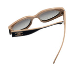 Chanel sunglasses with beige frame and black accents on a white background