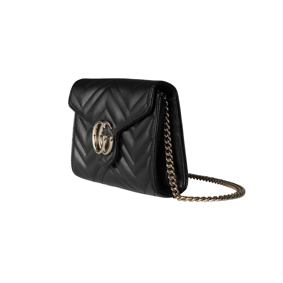 Black quilted handbag with gold chain on a light gray background