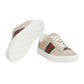 Beige sneakers with green and red stripes on a light gray background