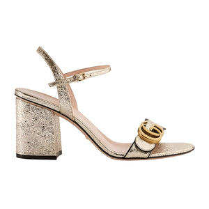 Gold high-heeled shoe with Gucci logo on a white background