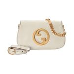 White handbag with gold chain and logo on a light gray background